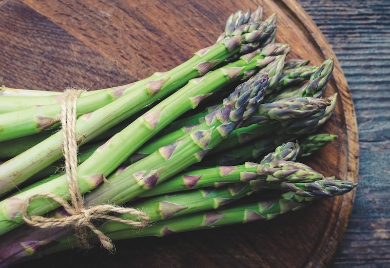 Asparagus bundle tied together on round wooden board