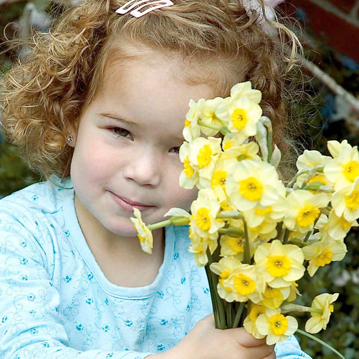 young girl holding bunch of daffodils