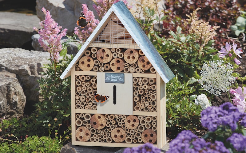 Wooden insect hotel with blue roof and butterfly