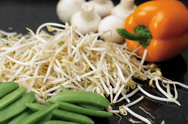Yellow beansprouts next to peas, peppers and mushrooms