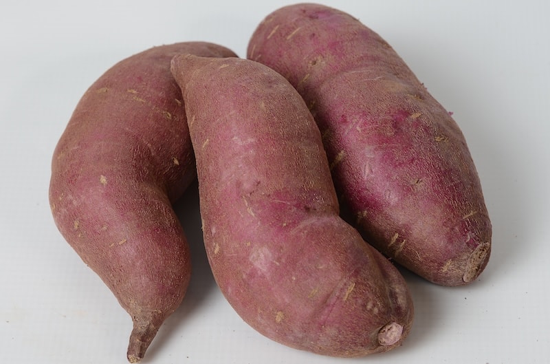 Three sweet potatoes against white background