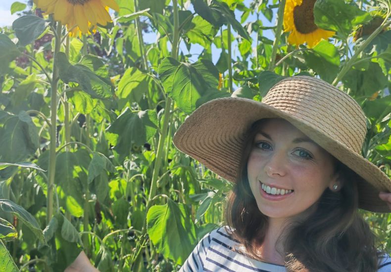 Ellen Dolbear under tall, homegrown sunflowers